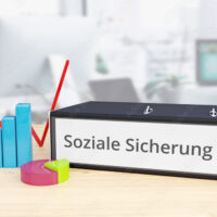 Soziale Sicherung – Finanzen/Wirtschaft. Ordner auf Schreibtisch mit Beschriftung neben Diagrammen. Business, Statistik